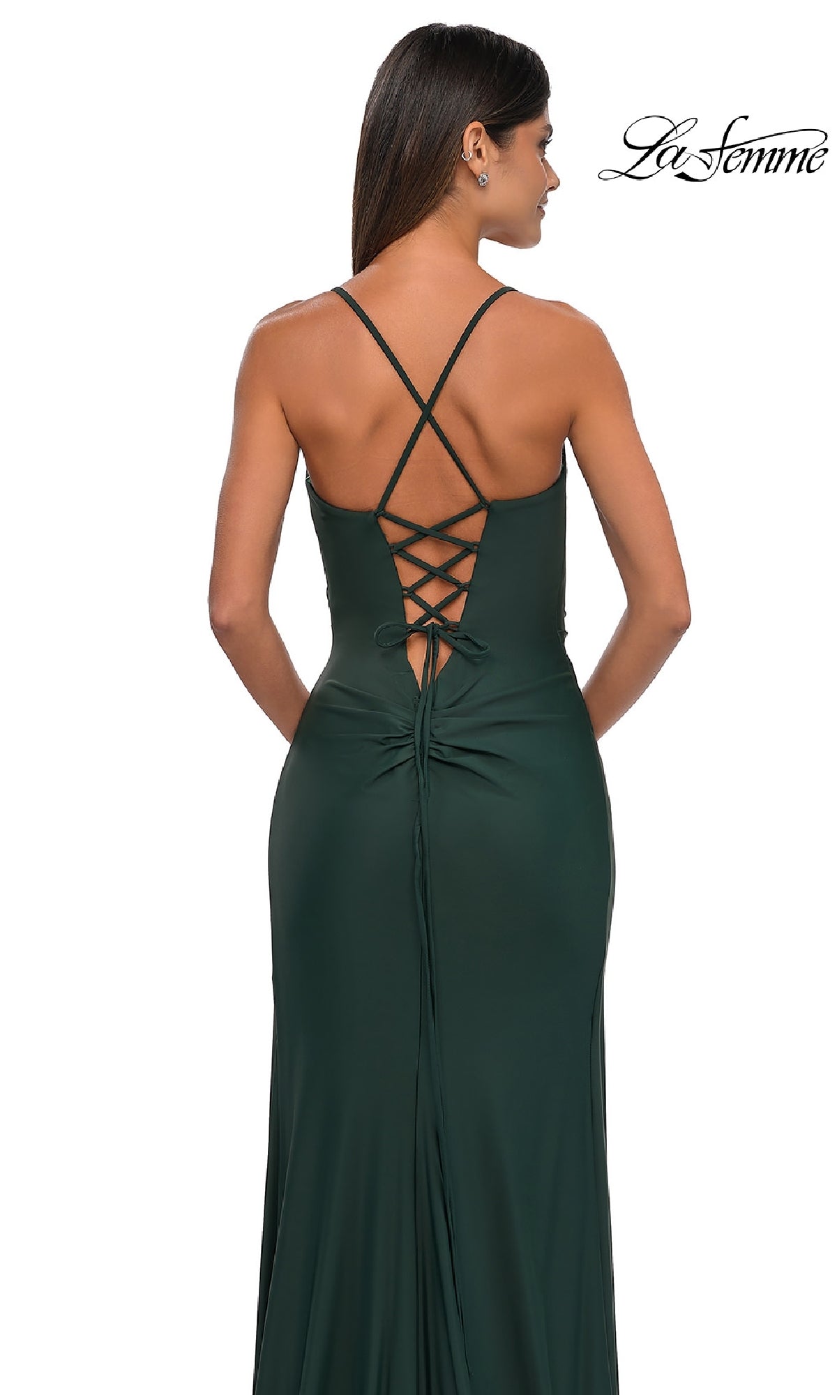 A woman models the Lace-Up Simple Long Prom Dress: La Femme 33103 in dark green, featuring a lace-up back and crossed straps, shown from behind on a white background. The La Femme logo appears in the top right corner.